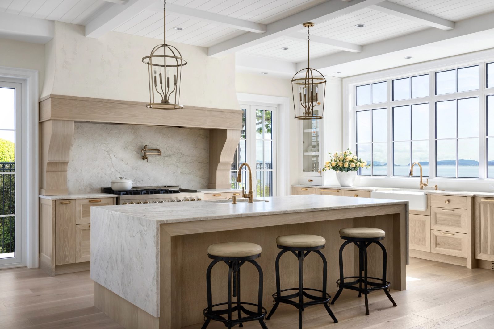 Kitchen — oak island, plaster hood, marble slab, window wall to the water