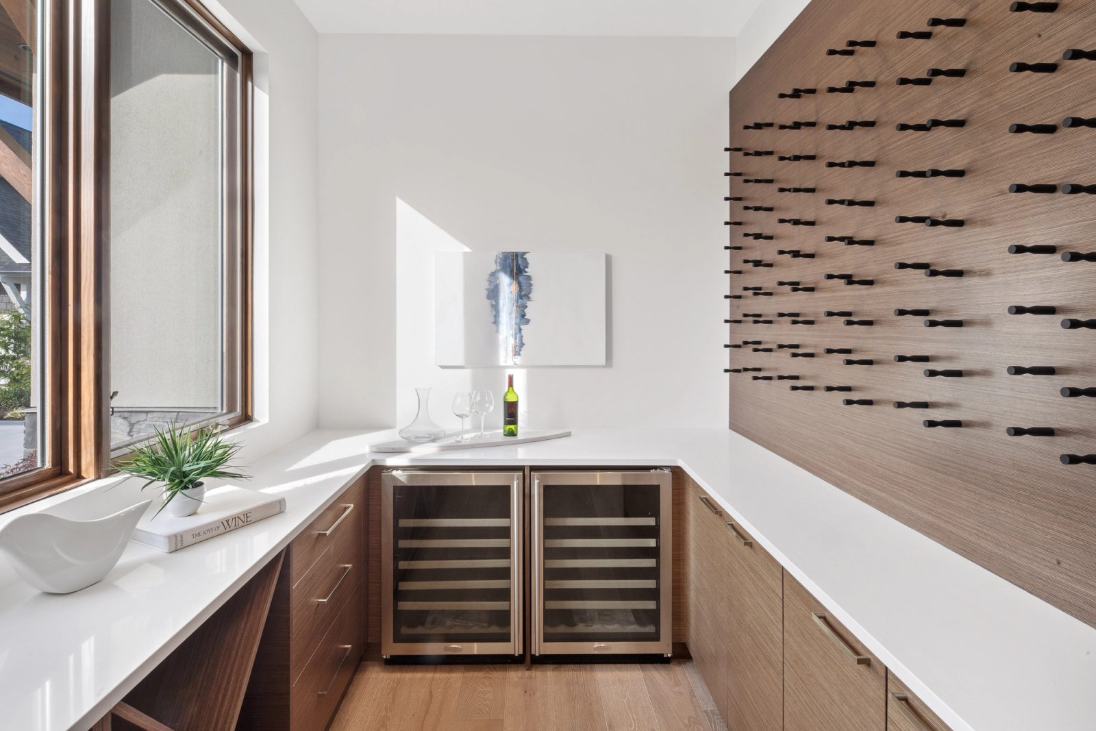 Wine room with a walnut bottle wall, two glass-fronted coolers and a quartz counter under a window
