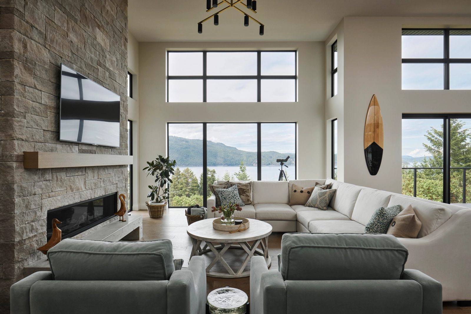 Living room with stacked stone fireplace and two-storey window wall over the channel