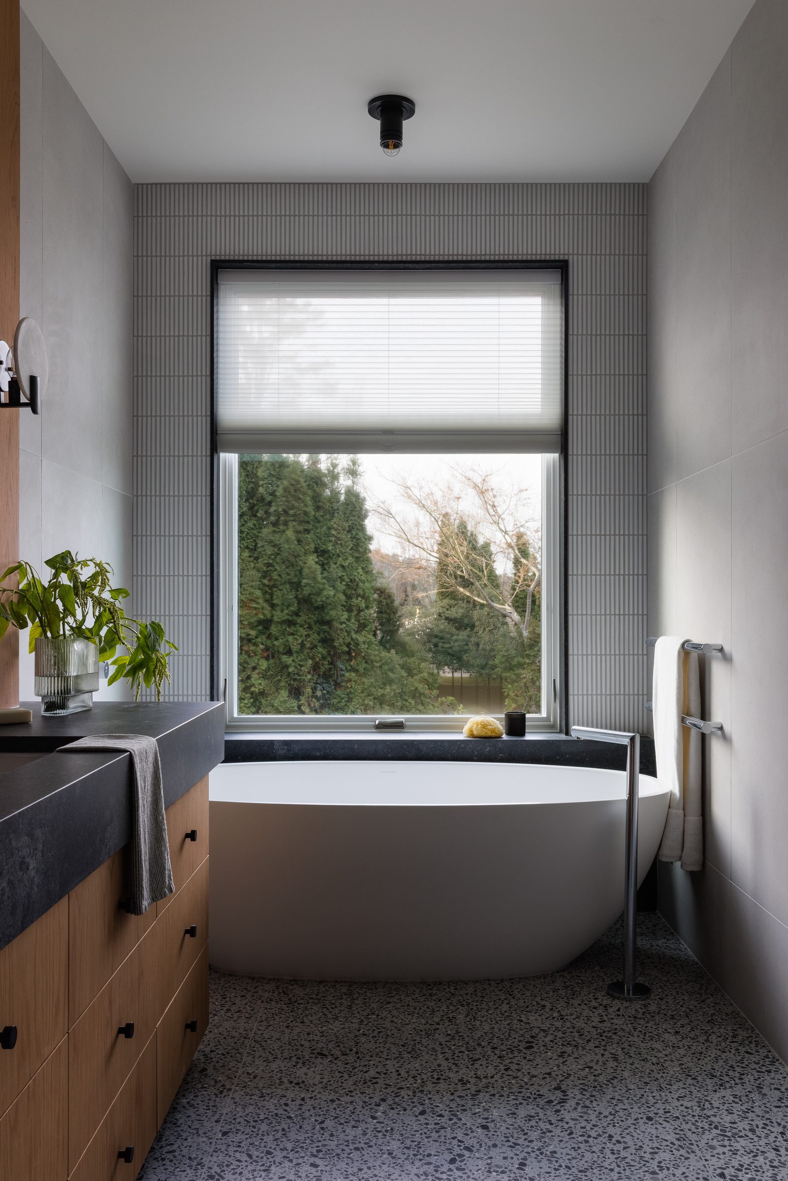 Right: the same tub set beneath a window with the blind half down, terrazzo underfoot.