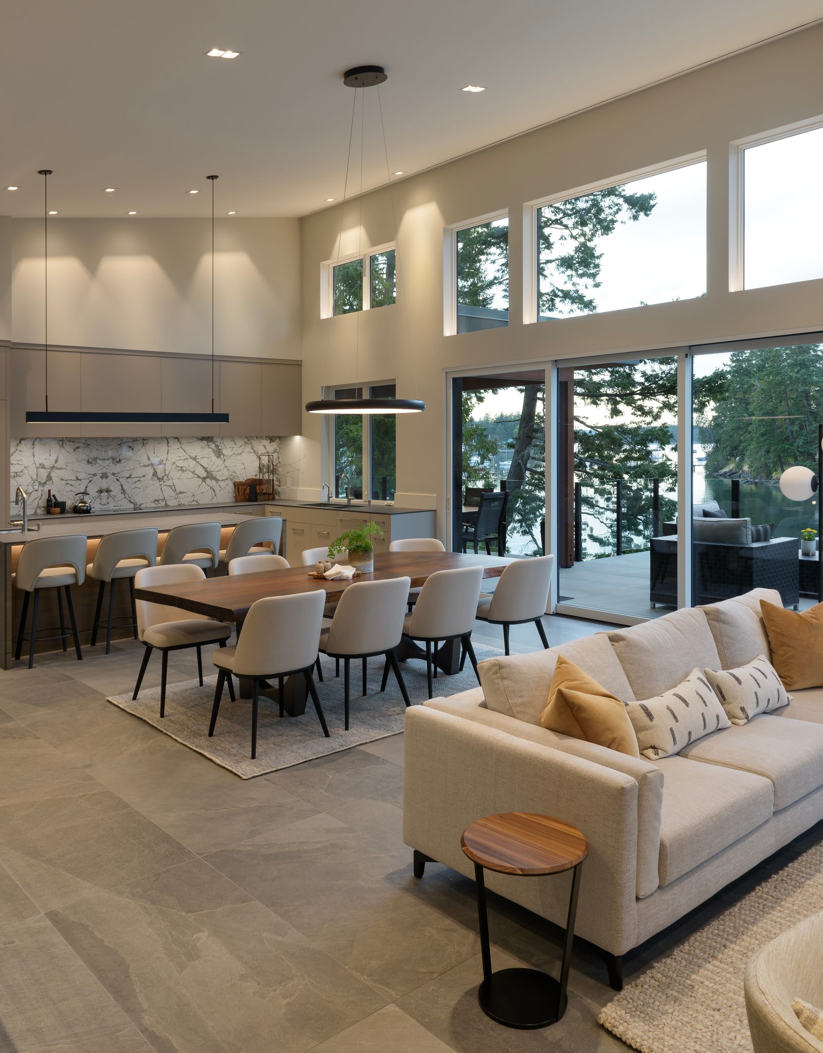Kitchen, dining and living in one volume under clerestory windows, opening to a deck above the water