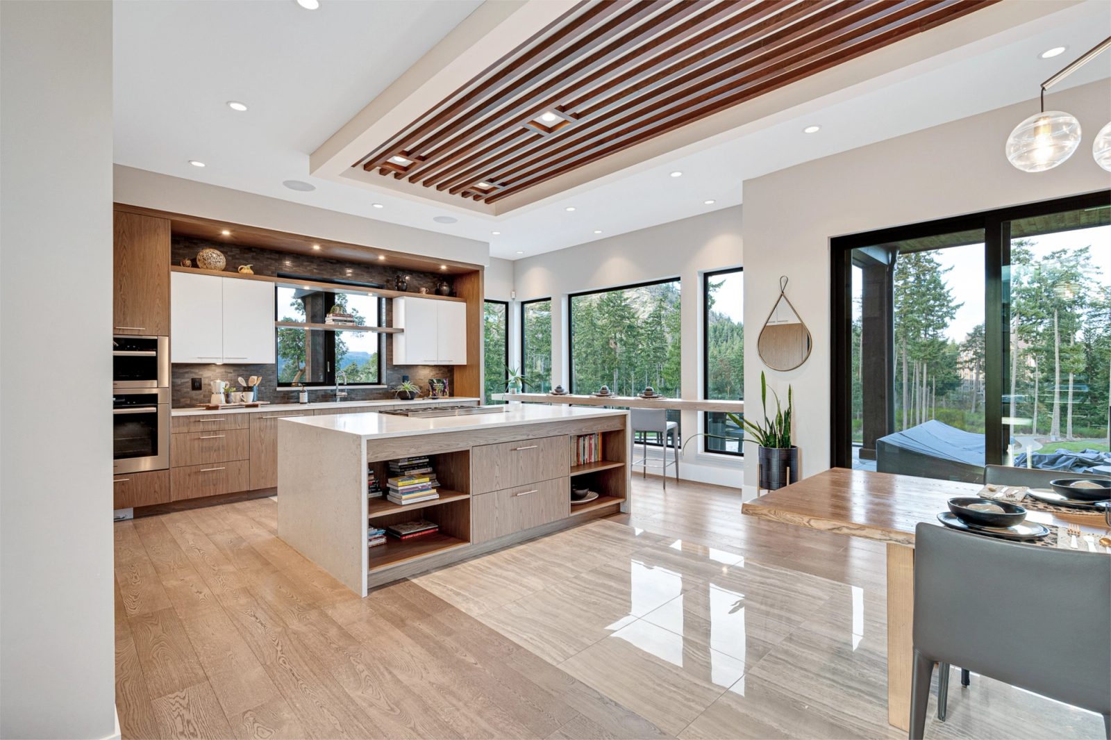 Open kitchen and dining room beneath a walnut slat ceiling, with a quartz island and a live-edge table