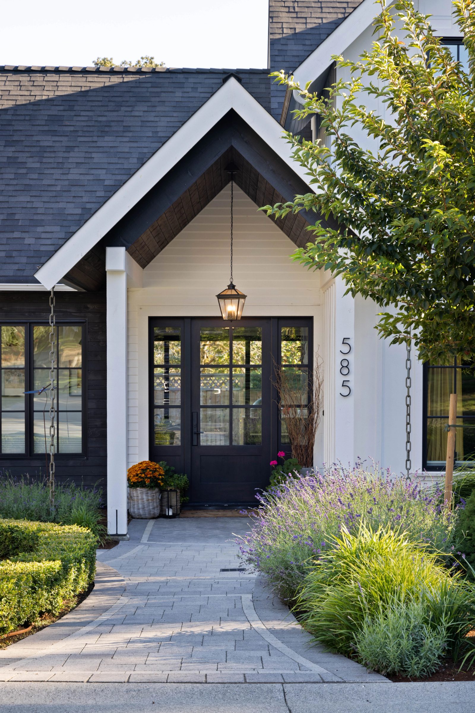 Gabled entry porch with a hanging lantern, glazed double doors and lavender massed along a paver walk