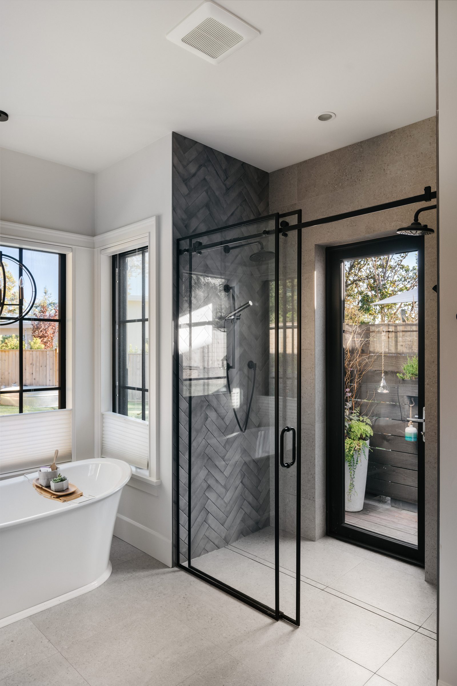 Ensuite with a freestanding tub, a charcoal herringbone shower and a glazed door to a private outdoor shower garden