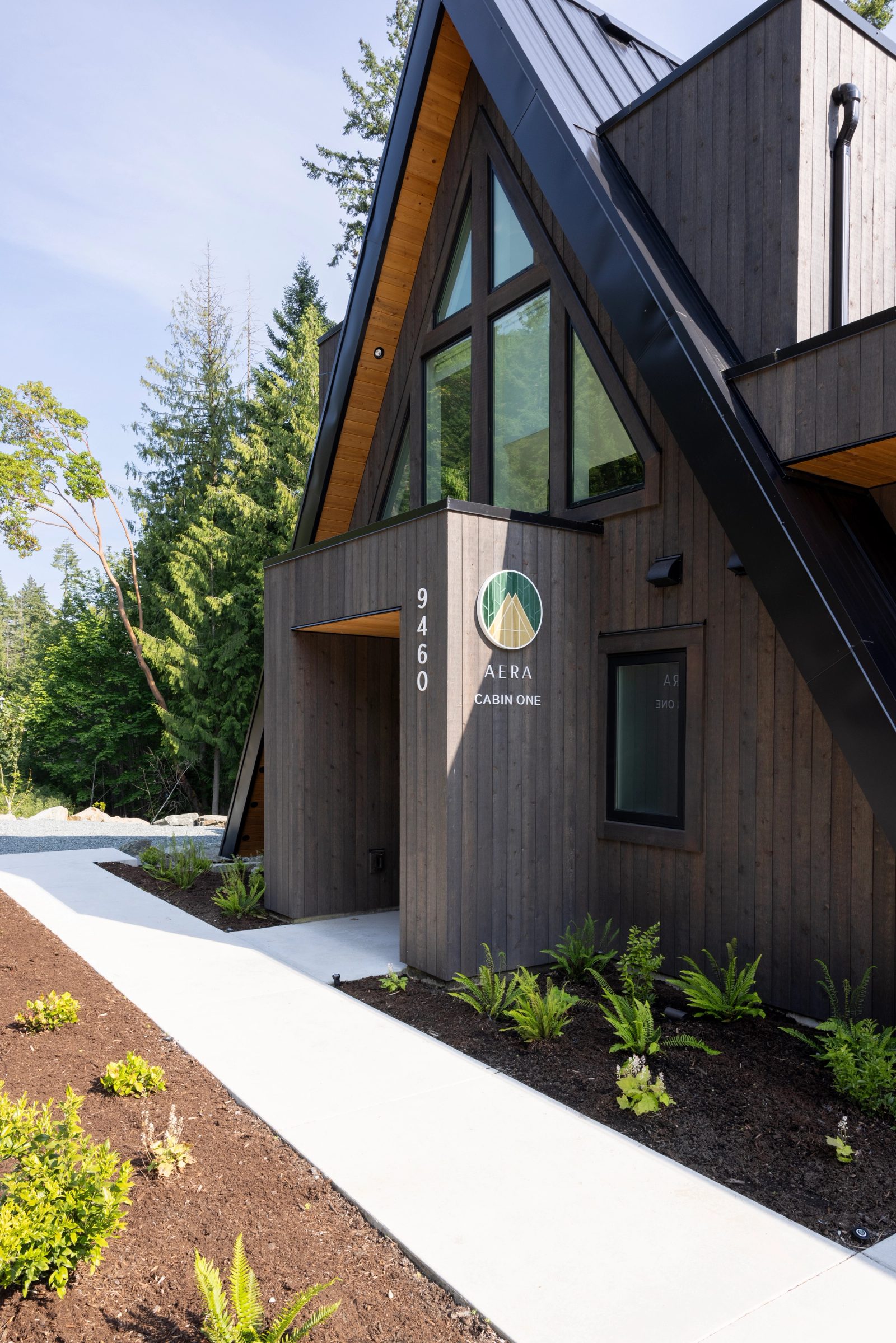 Cabin entry with a circular carved sign on dark stained cedar siding