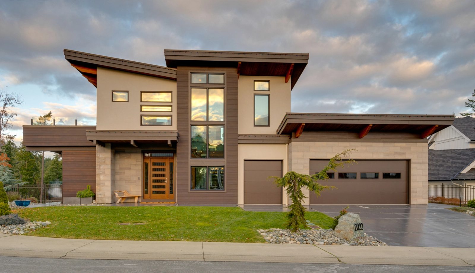 Street elevation of a contemporary house at dusk, with deep cedar soffits and a fir entry door under a projecting canopy