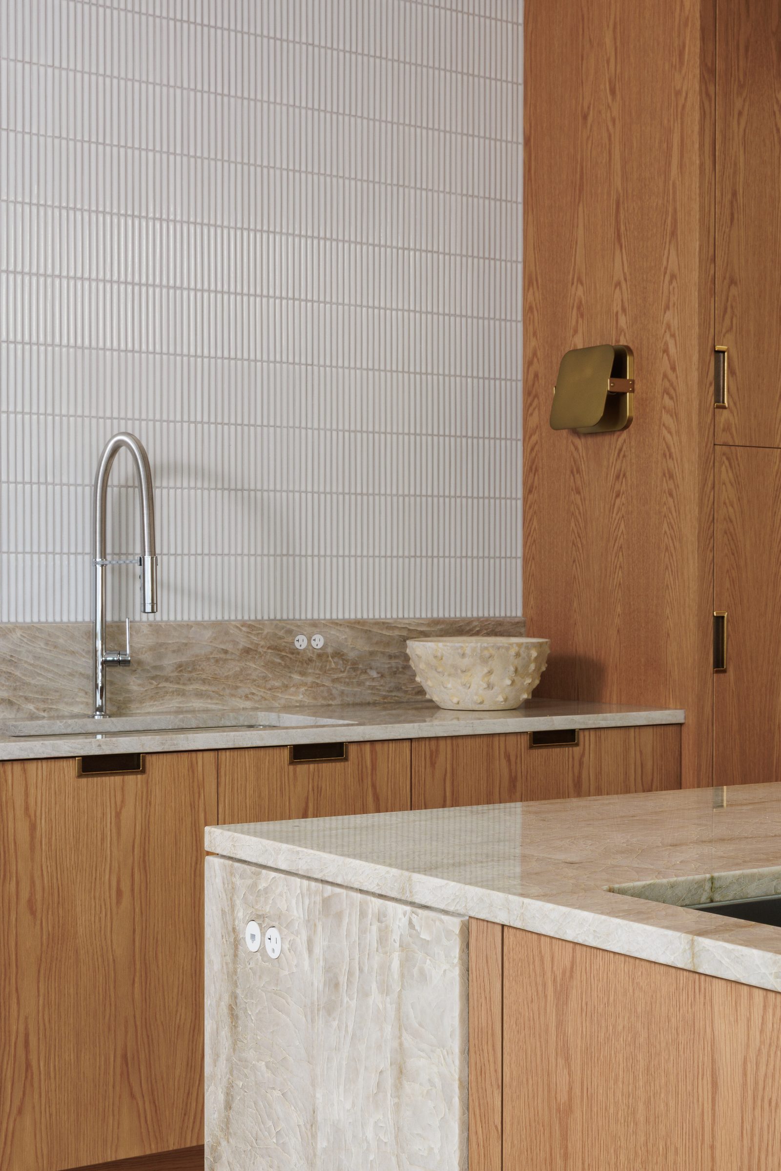 Right: a counter corner in quartzite, a brass sconce on an oak panel and a ceramic bowl on the run.