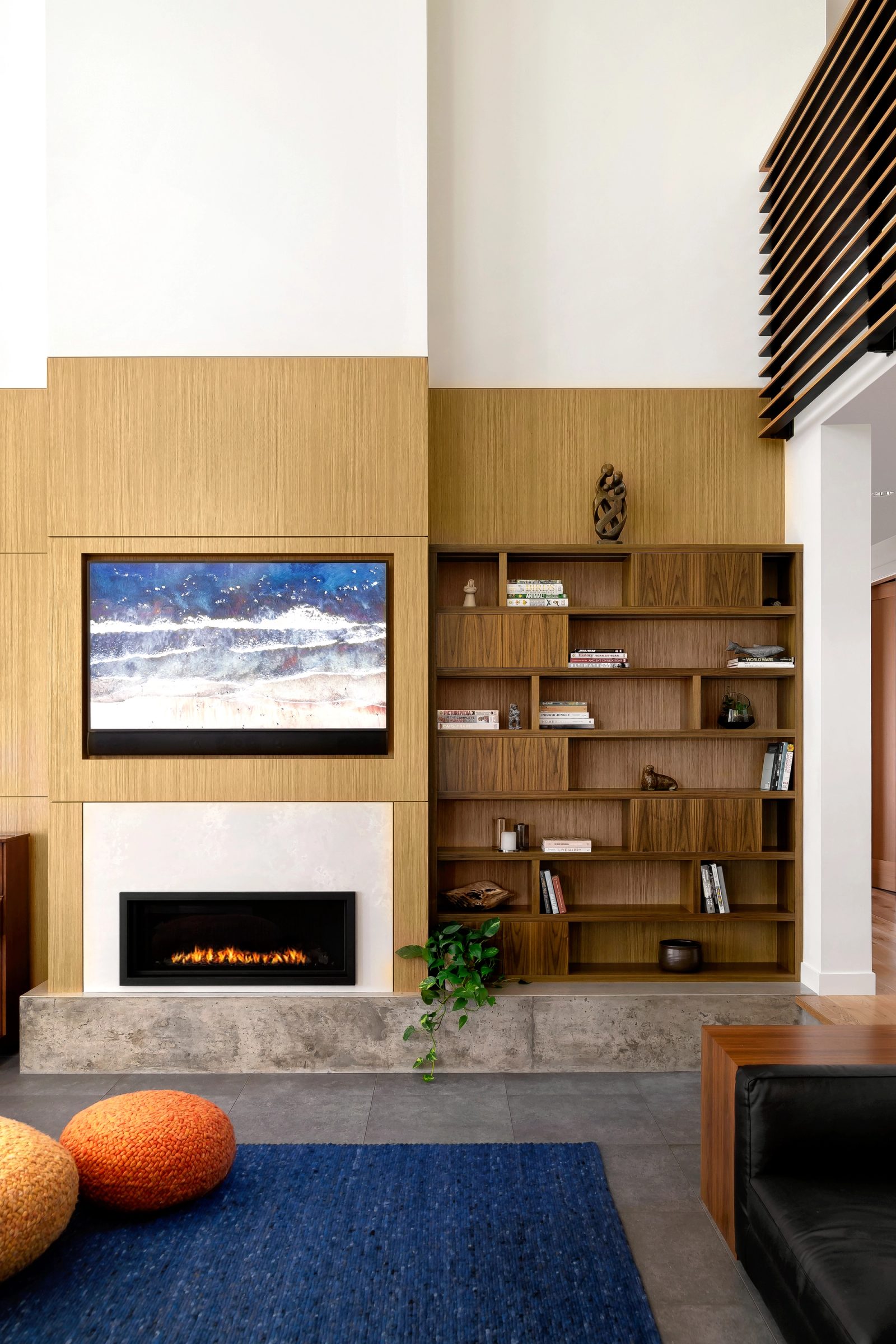 Oak-panelled fireplace wall with a walnut bookcase on a board-formed concrete hearth
