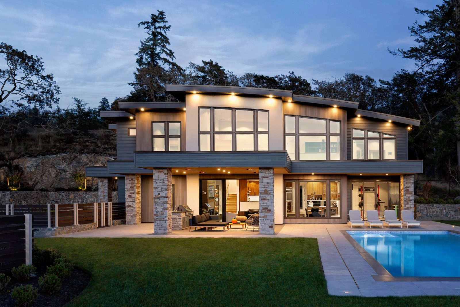 Rear elevation at dusk, terrace and upper rooms lit, pool in the foreground