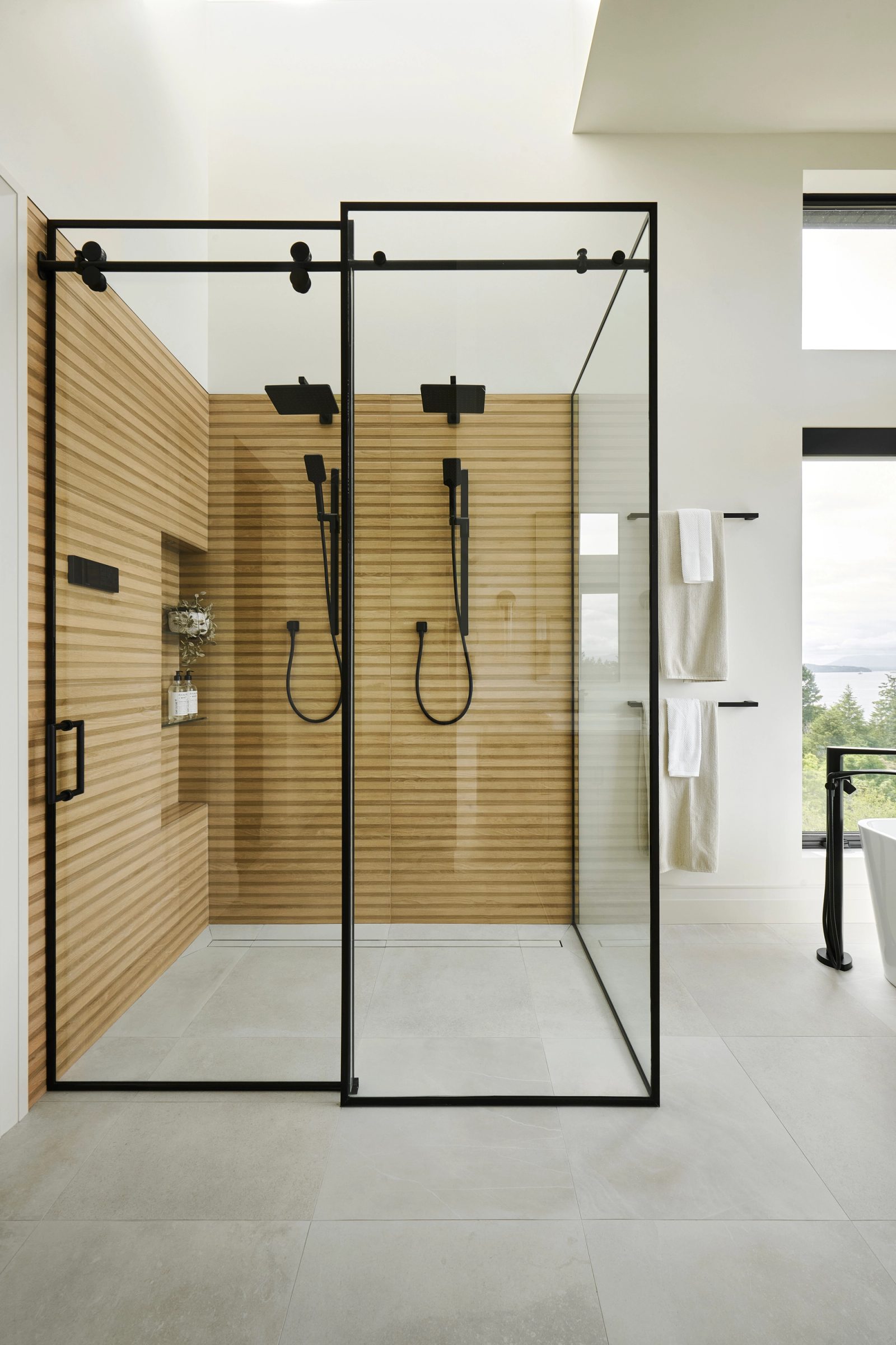 Walk-in shower lined in slatted wood behind frameless glass, twin rain heads