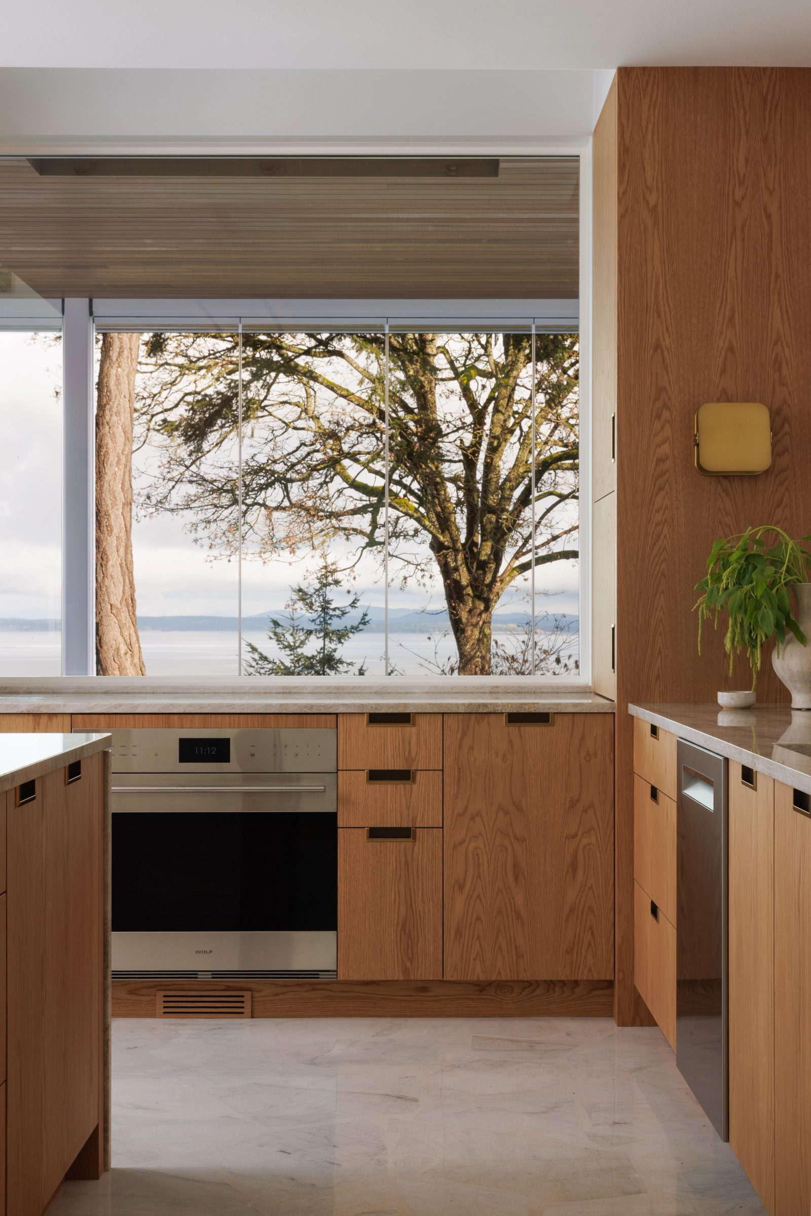 Left: a kitchen window filled by a moss-limbed tree, with open water and a forested far shore beyond it.