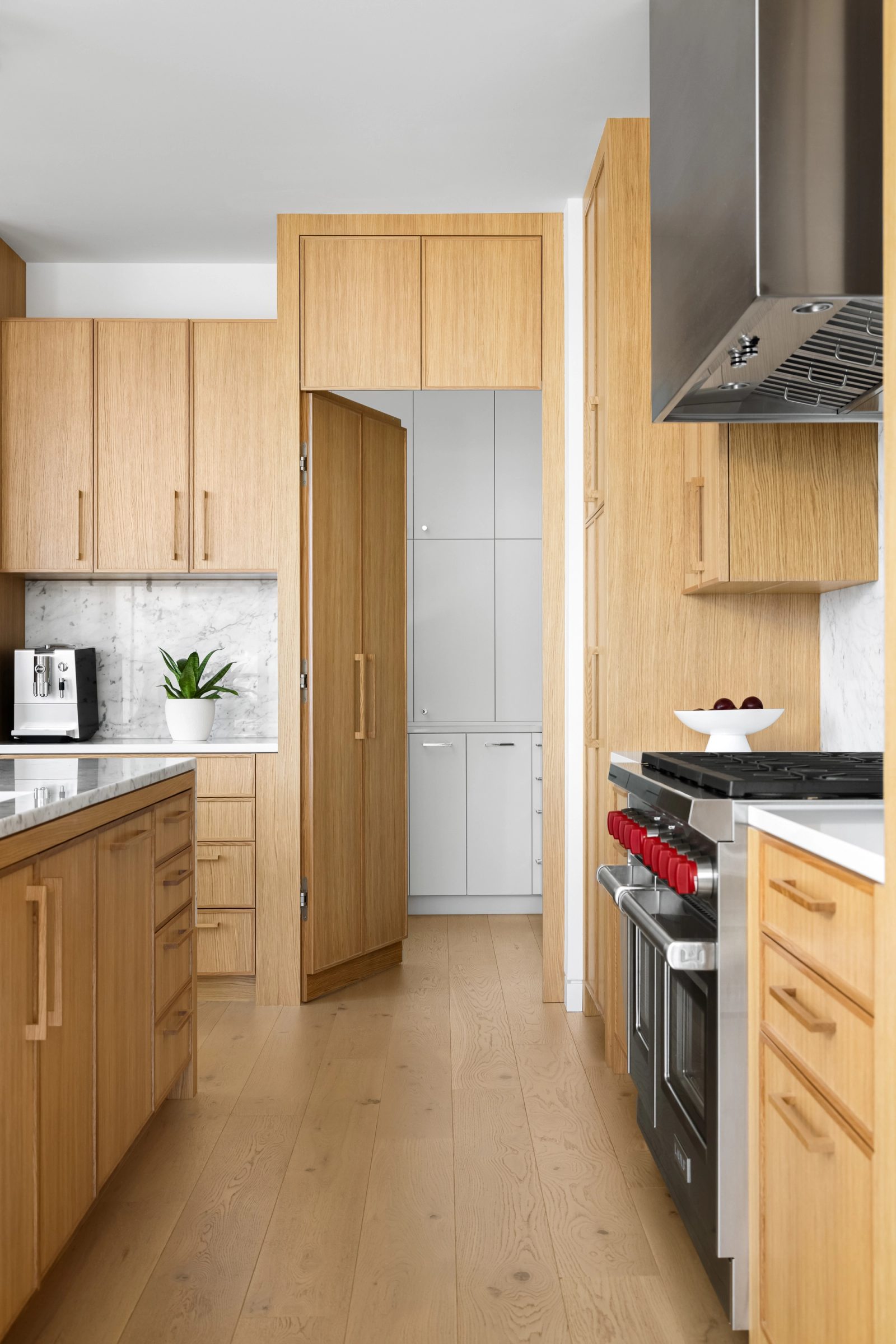 Oak door standing open from the kitchen to a service room fitted out in white.