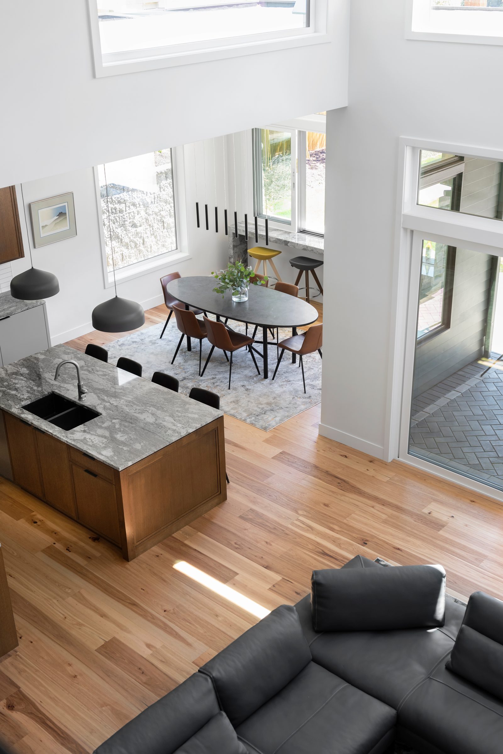 View down from the loft to the kitchen island, dining table and a counter passing through to the patio
