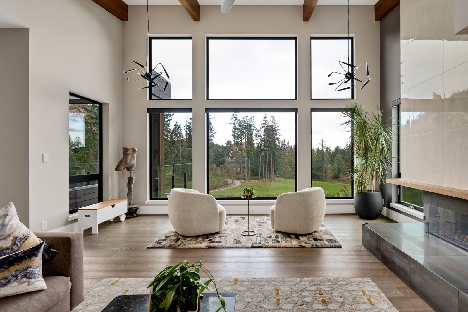 Living room looking out through a two-storey window wall to firs and the fairway