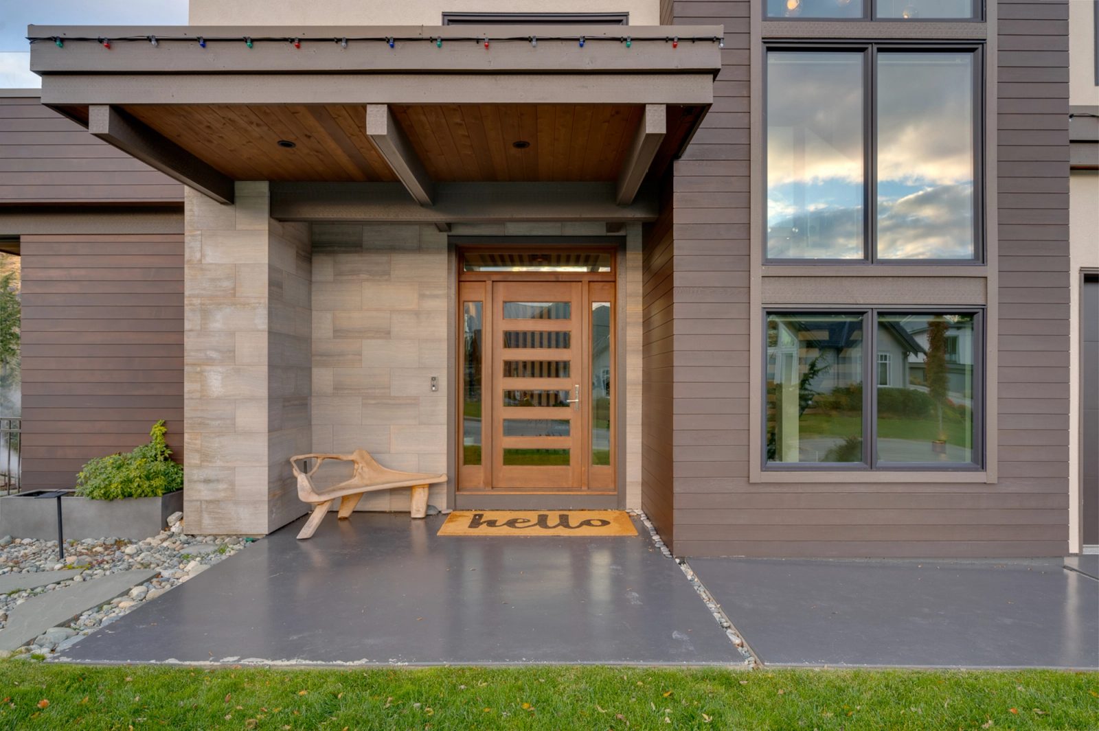 Covered entry with a five-panel fir door, board-formed stone and a carved bench on a poured concrete porch