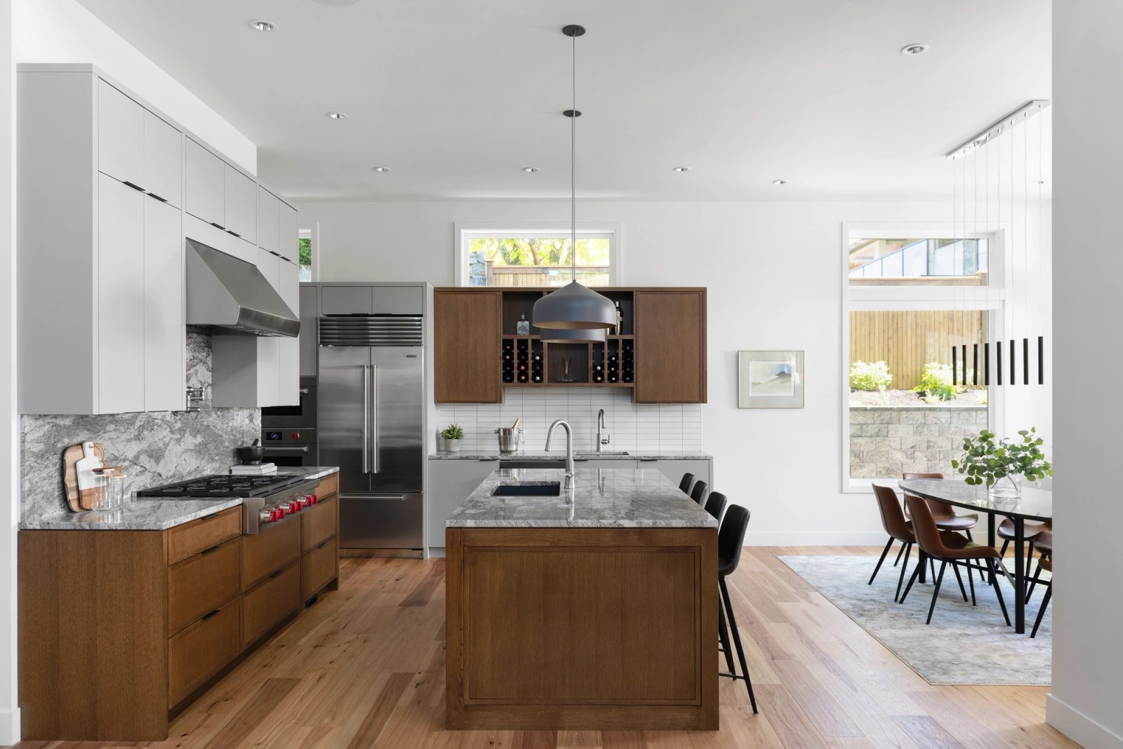Kitchen with oak cabinetry, quartzite counters, a stainless range and a dining table beyond