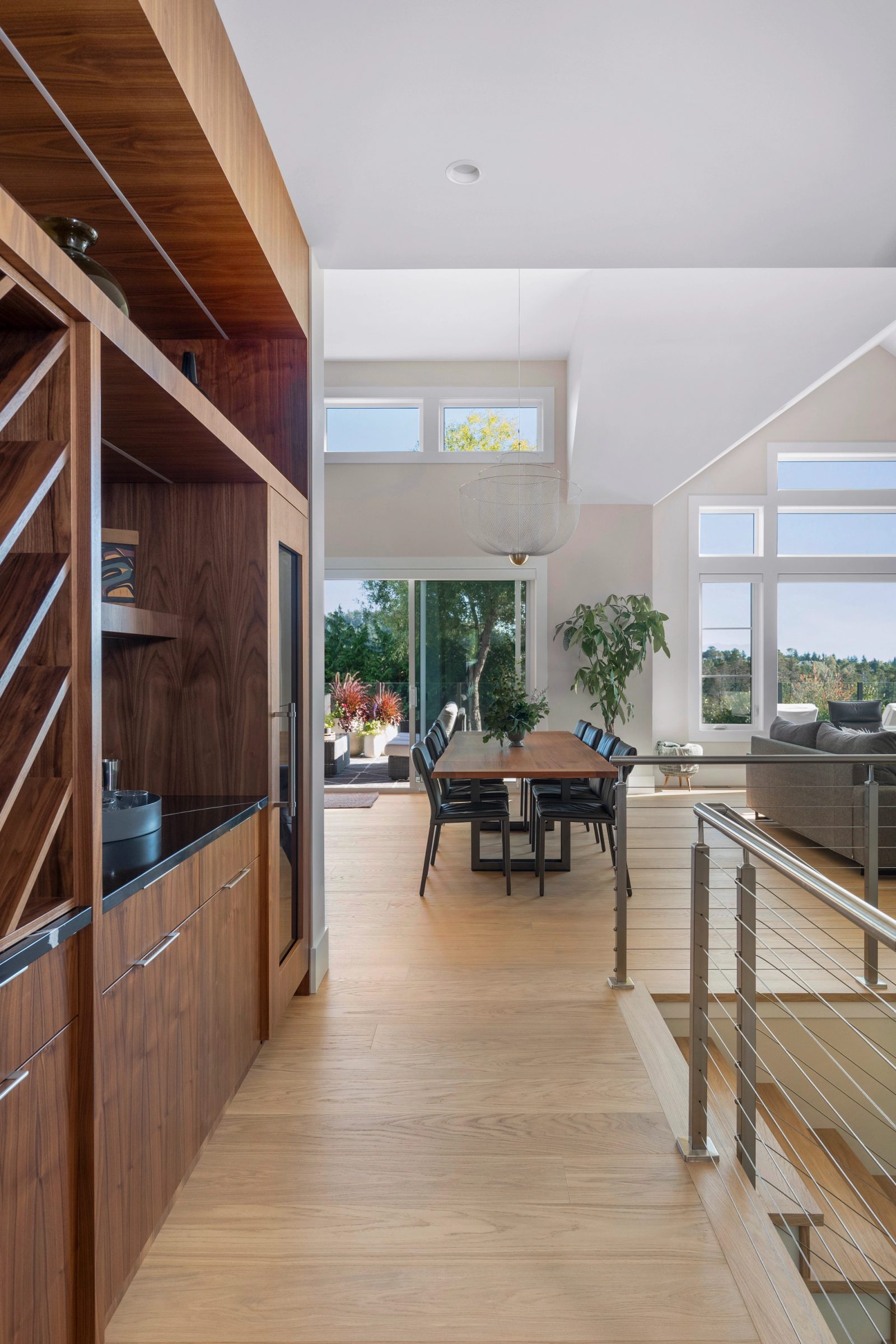 View past a walnut wine wall and bar to the dining table and the living room beyond