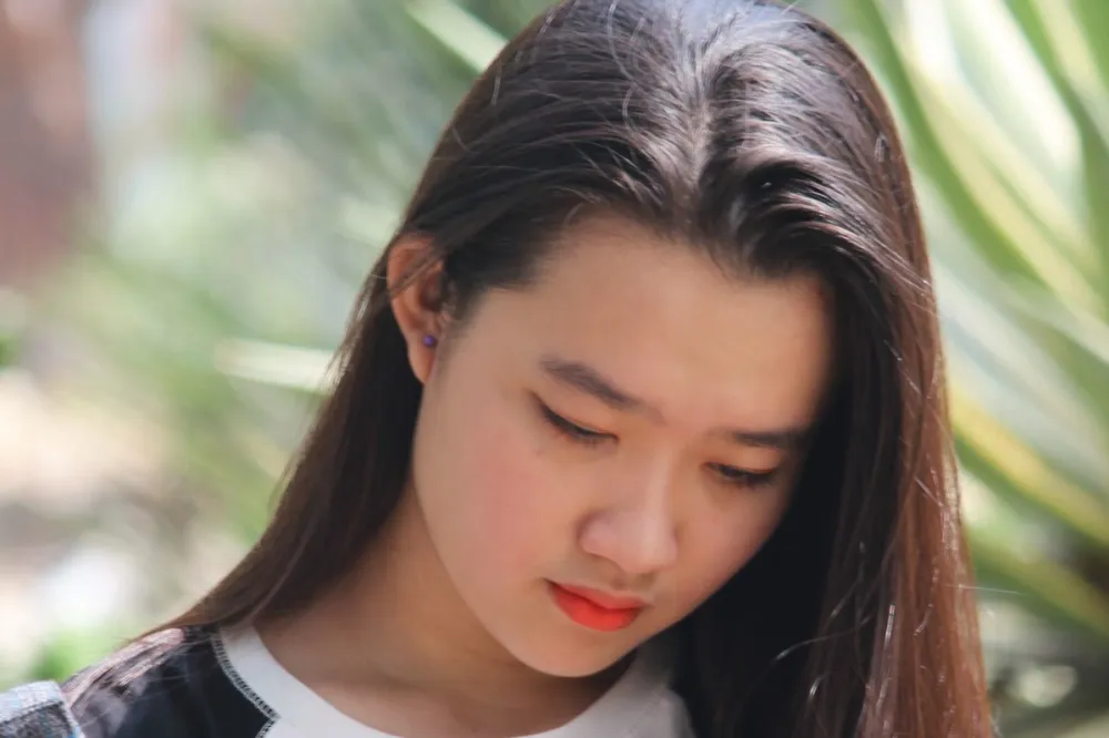긴 머리를 늘어뜨린 채 고개를 숙이고 아래를 내려다보는 여성