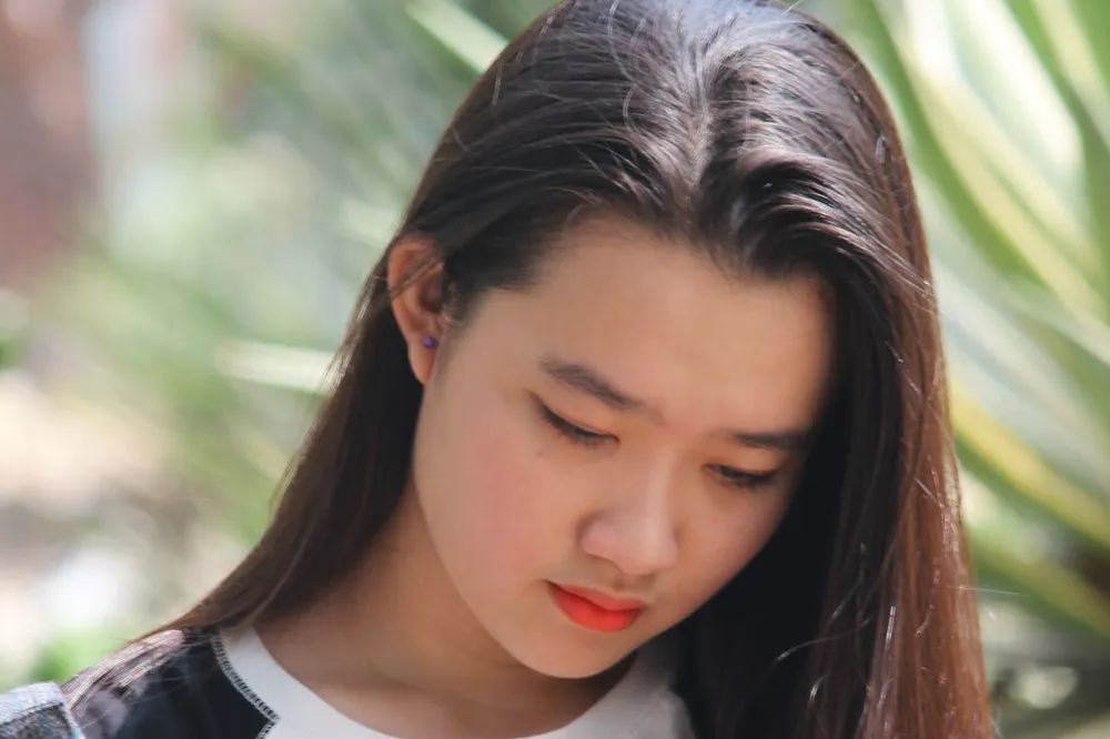 긴 머리를 늘어뜨린 채 고개를 숙이고 아래를 내려다보는 여성