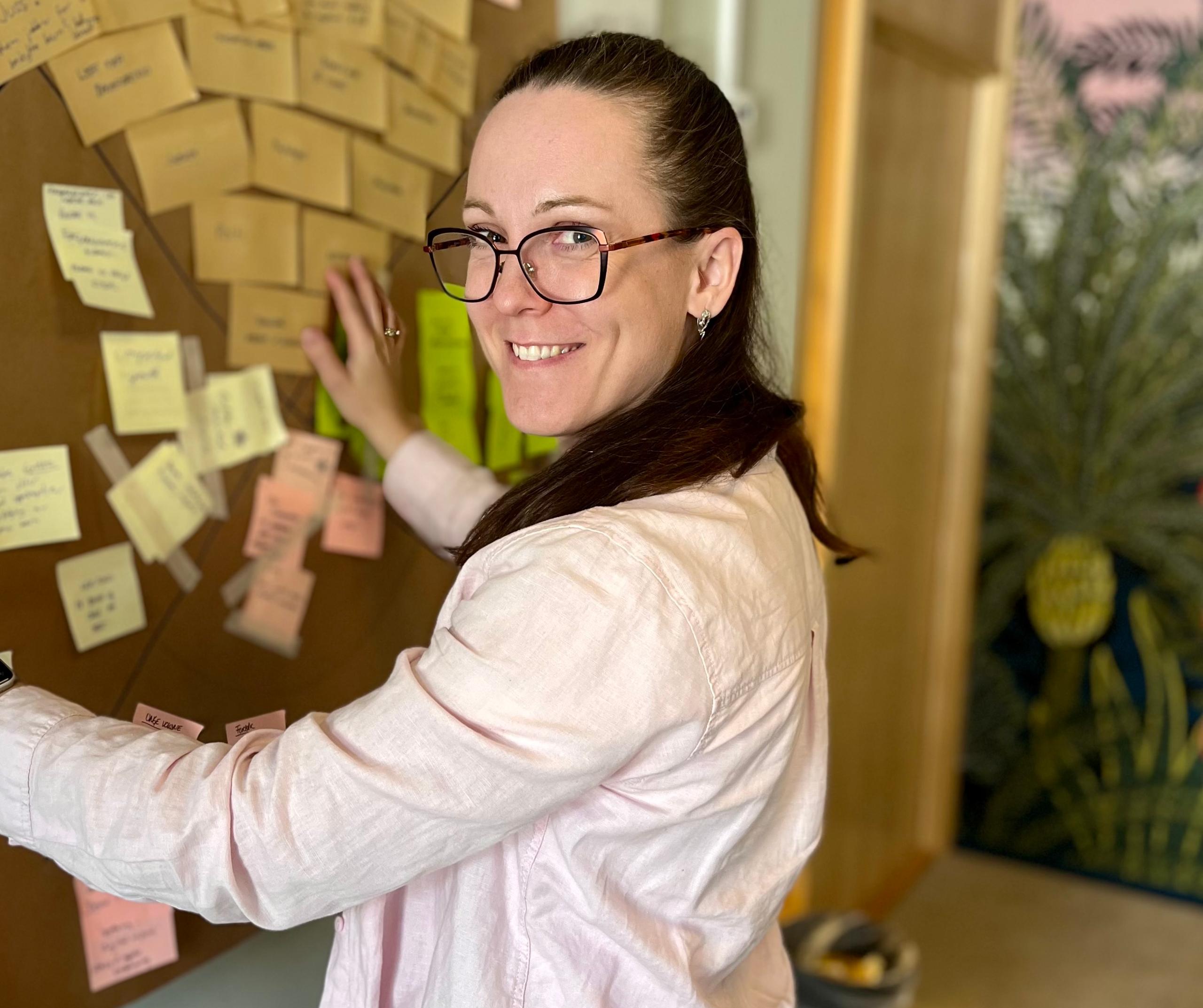 Anna Rabstad på Hamar-kontoret med vegg fylt av post-it lapper