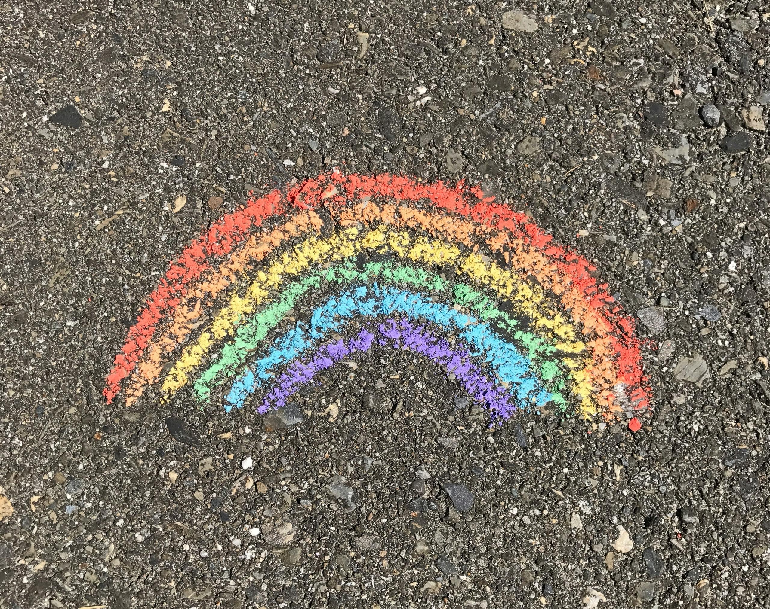Regnbue tegnet med kritt på asfalt som symboliserer Pride 