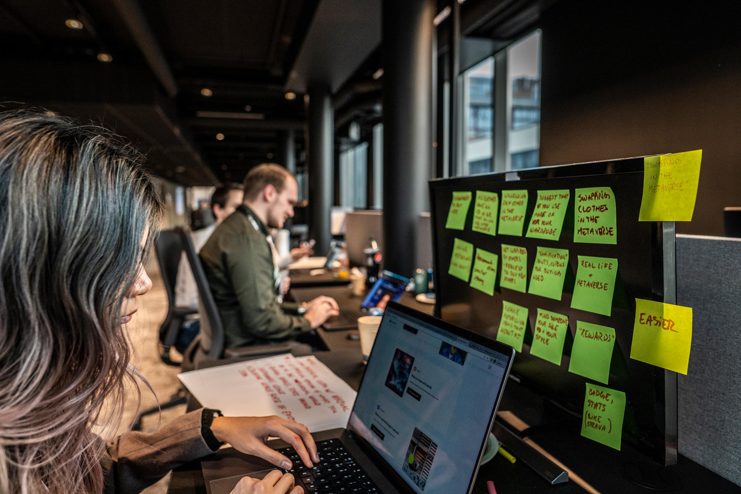 Inmetaer jobber på PCer, den nærmeste fylt med post-it lapper