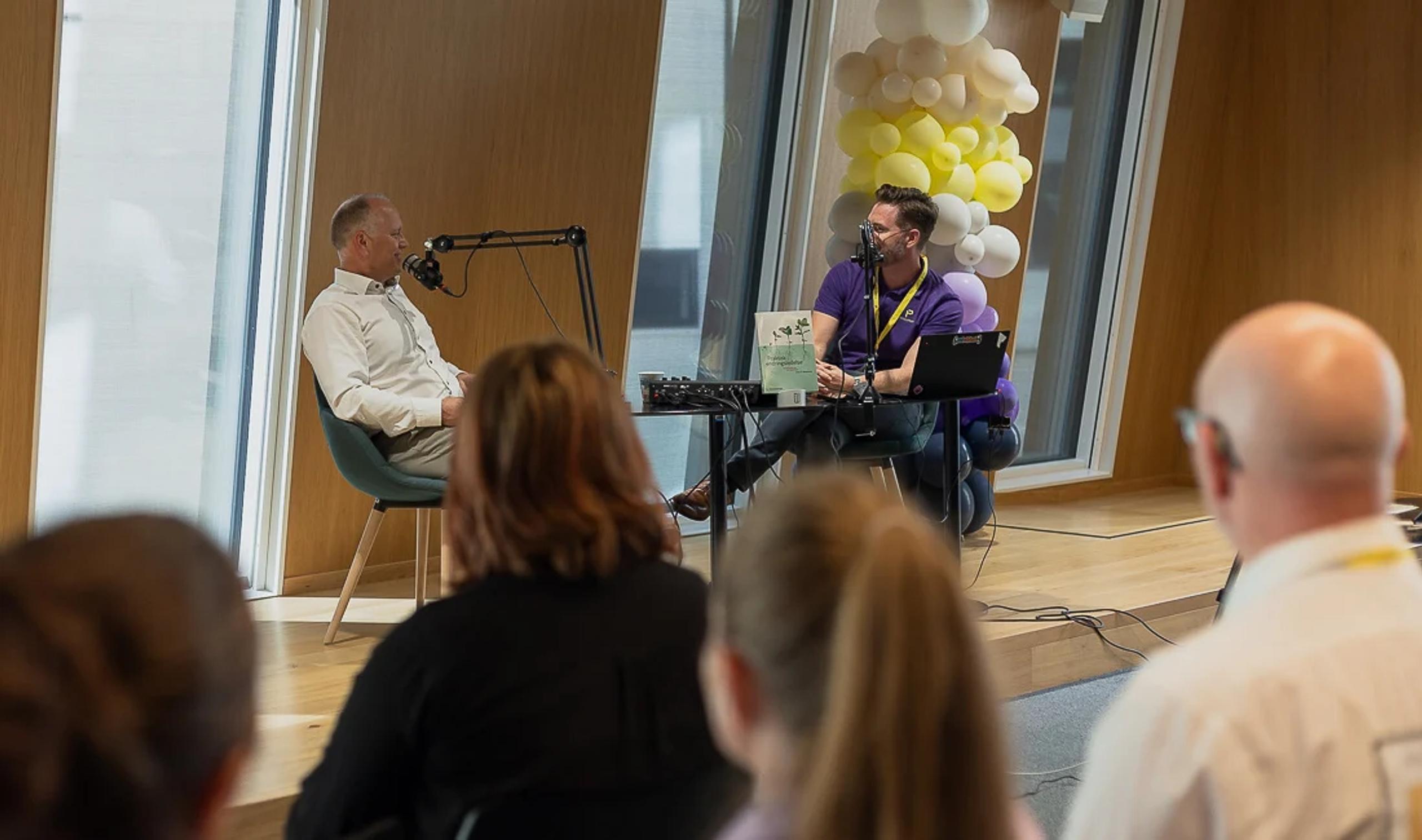 To personer som spiller inn podcast live på scenen