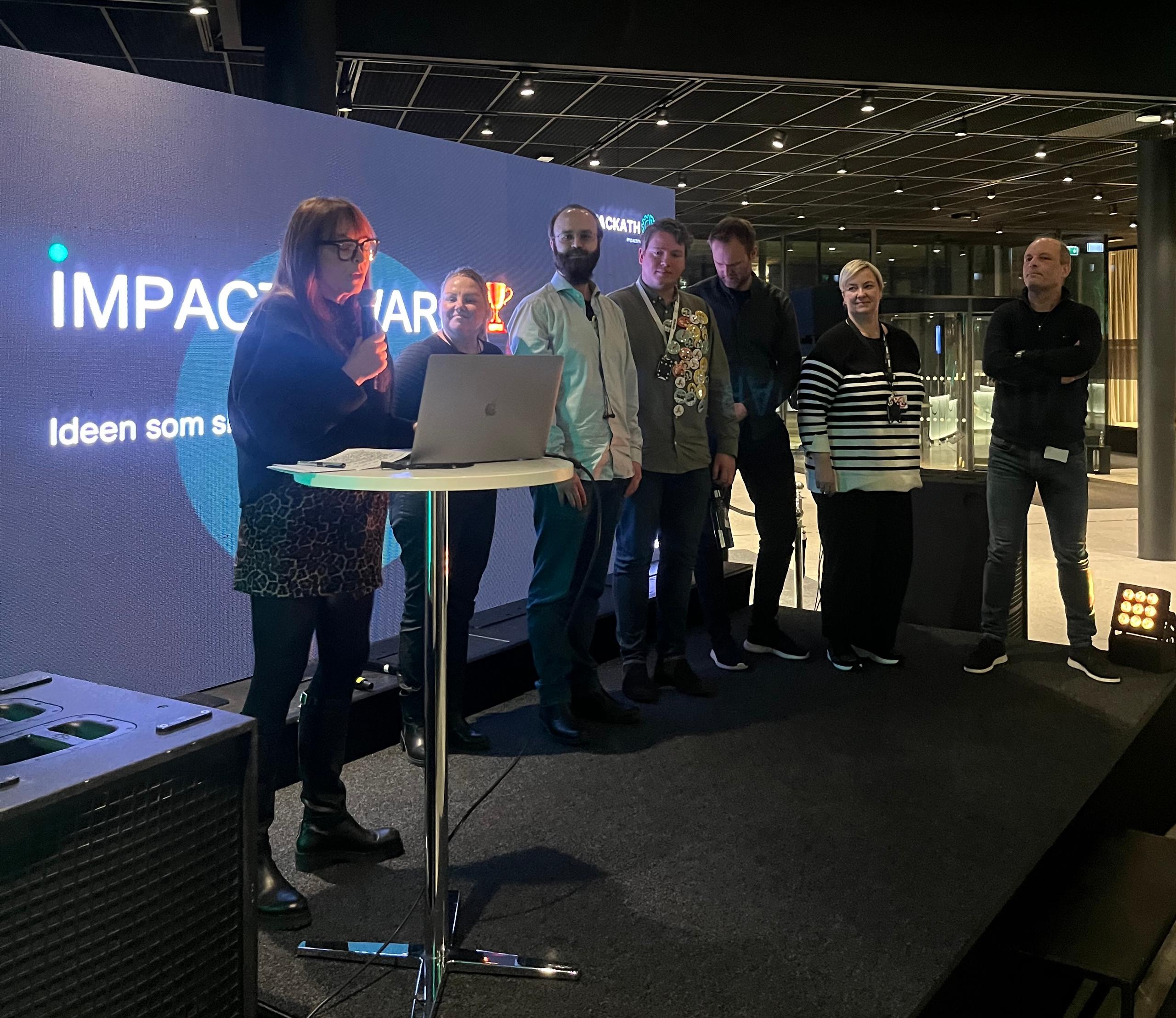 Linda Refvik deler ut Impact Award på scenen til vinnerlaget
