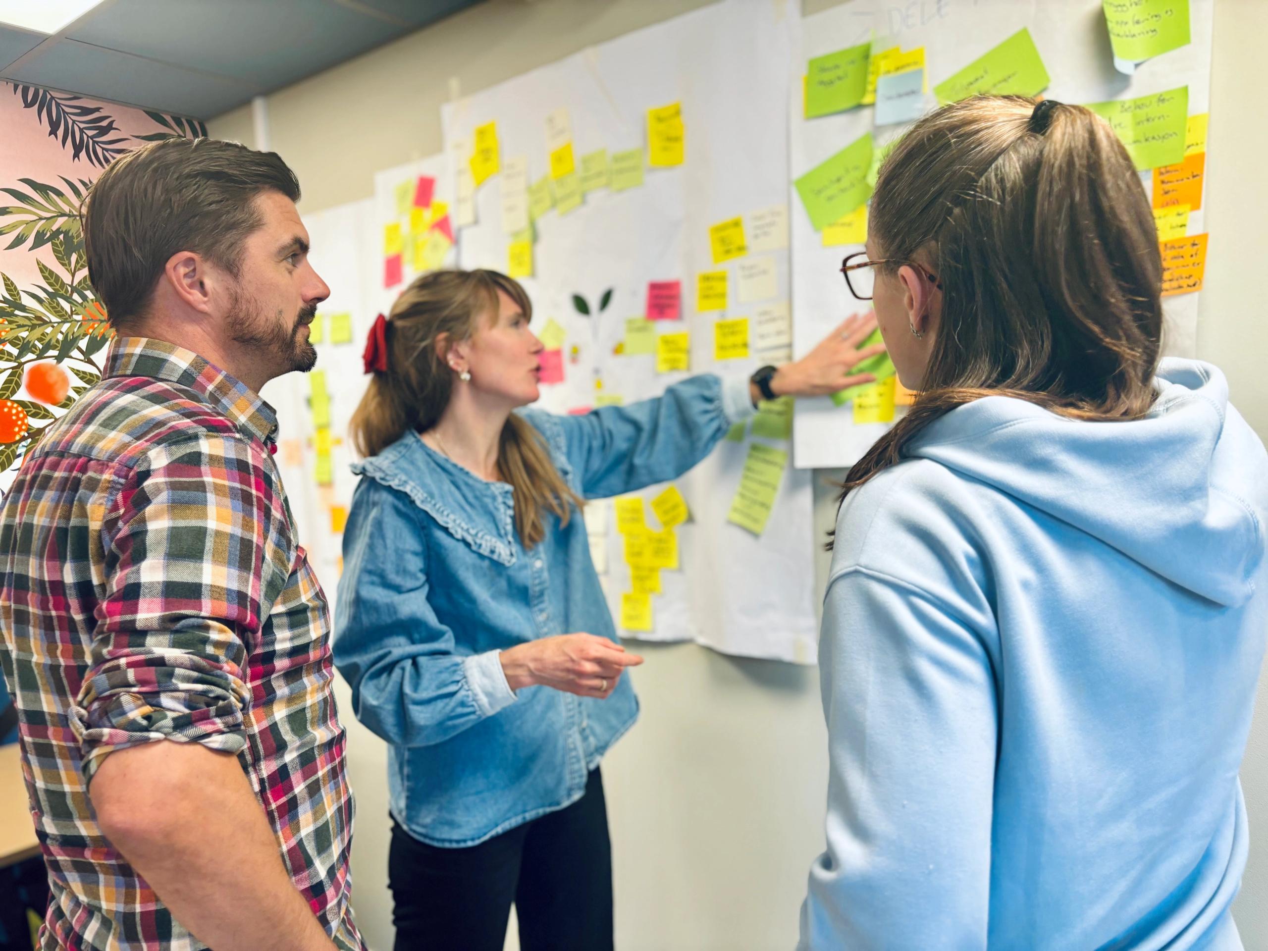 Tre kolleger i workshop med post-its på veggen