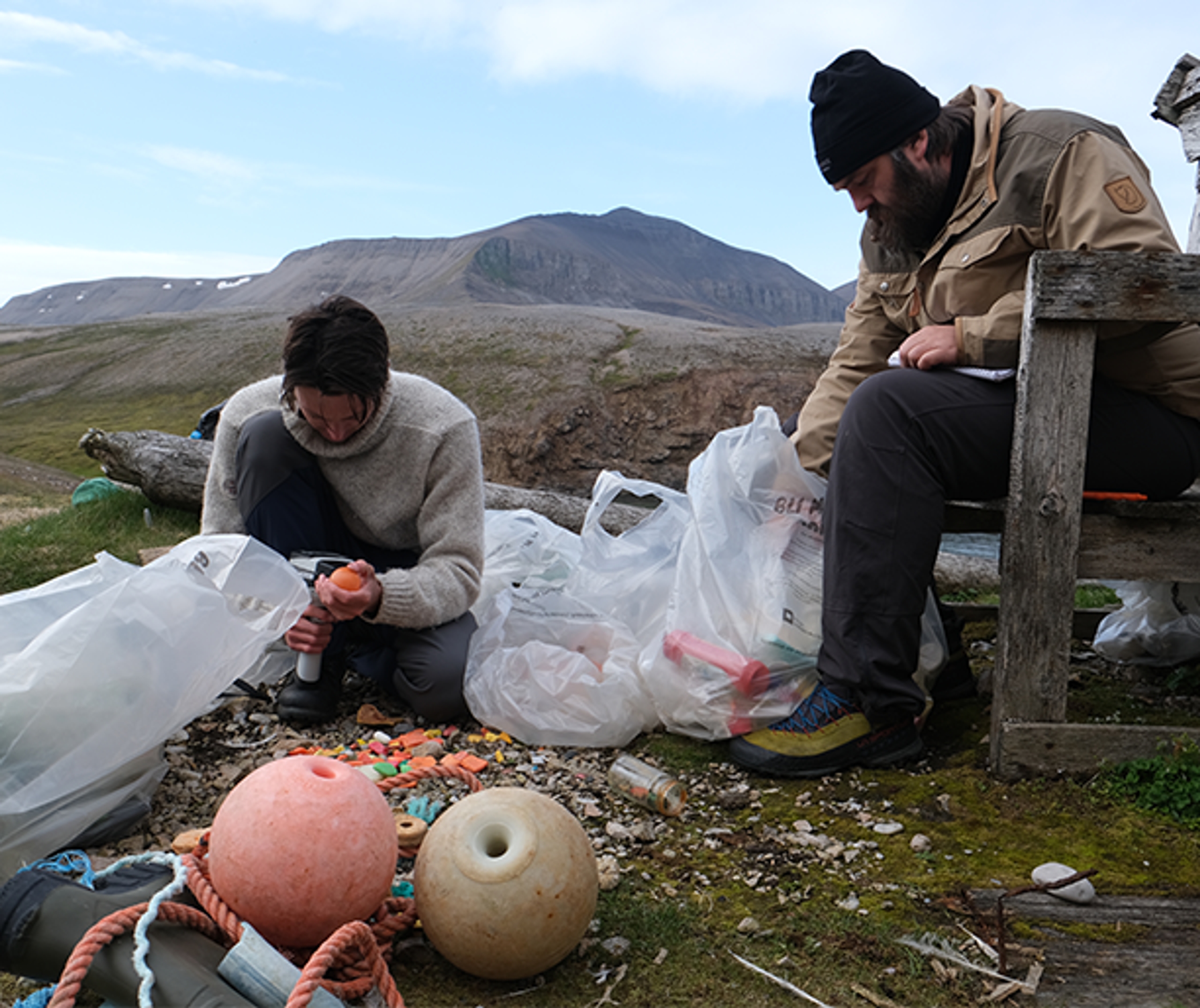 To personer går gjennom søppel og plast fra havet