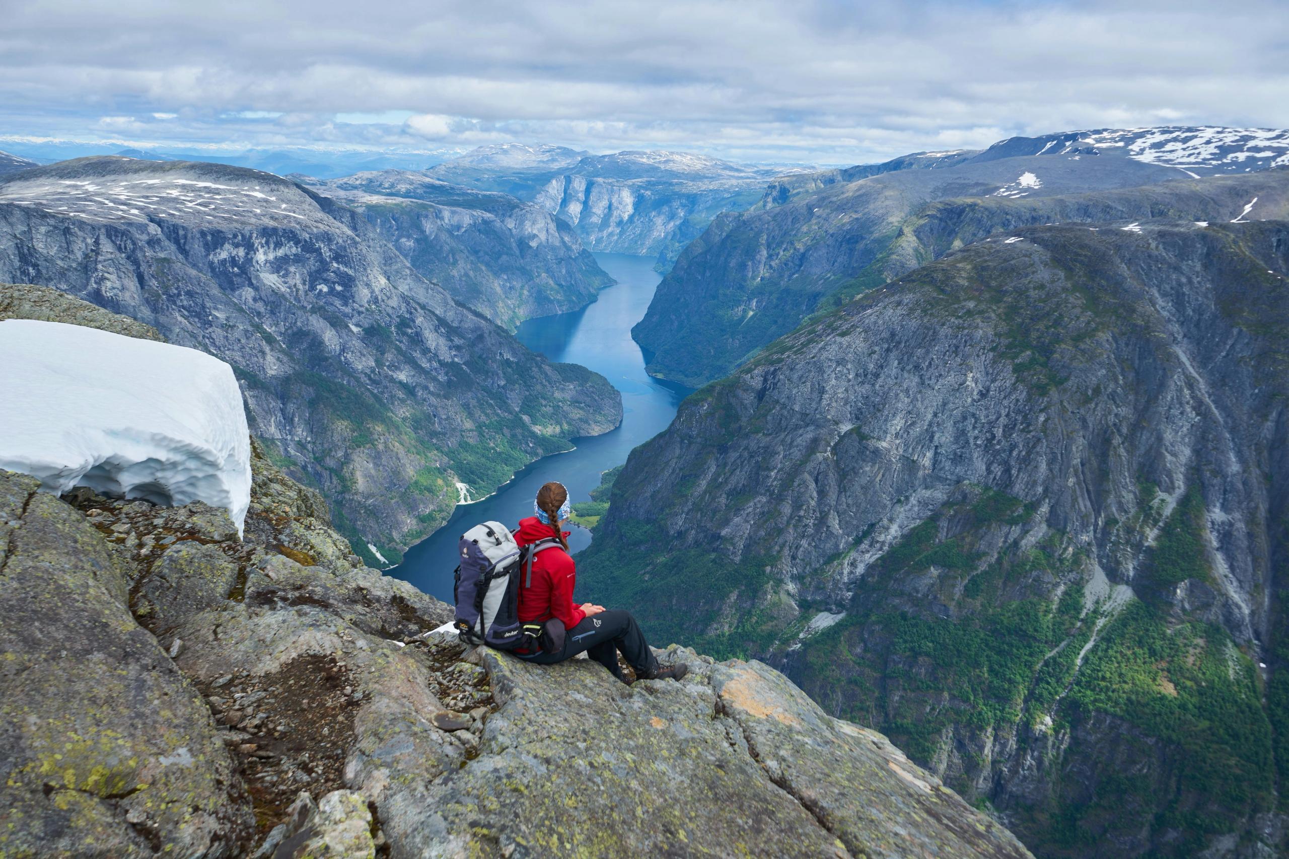 Sporty kvinne på fjelltopp ser utover landskap