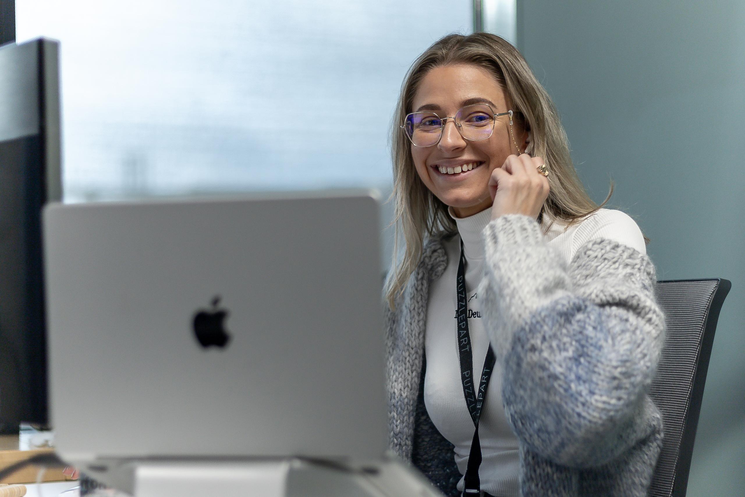 Anniken Olsen sitter foran en dataskjerm og smiler mot kamera