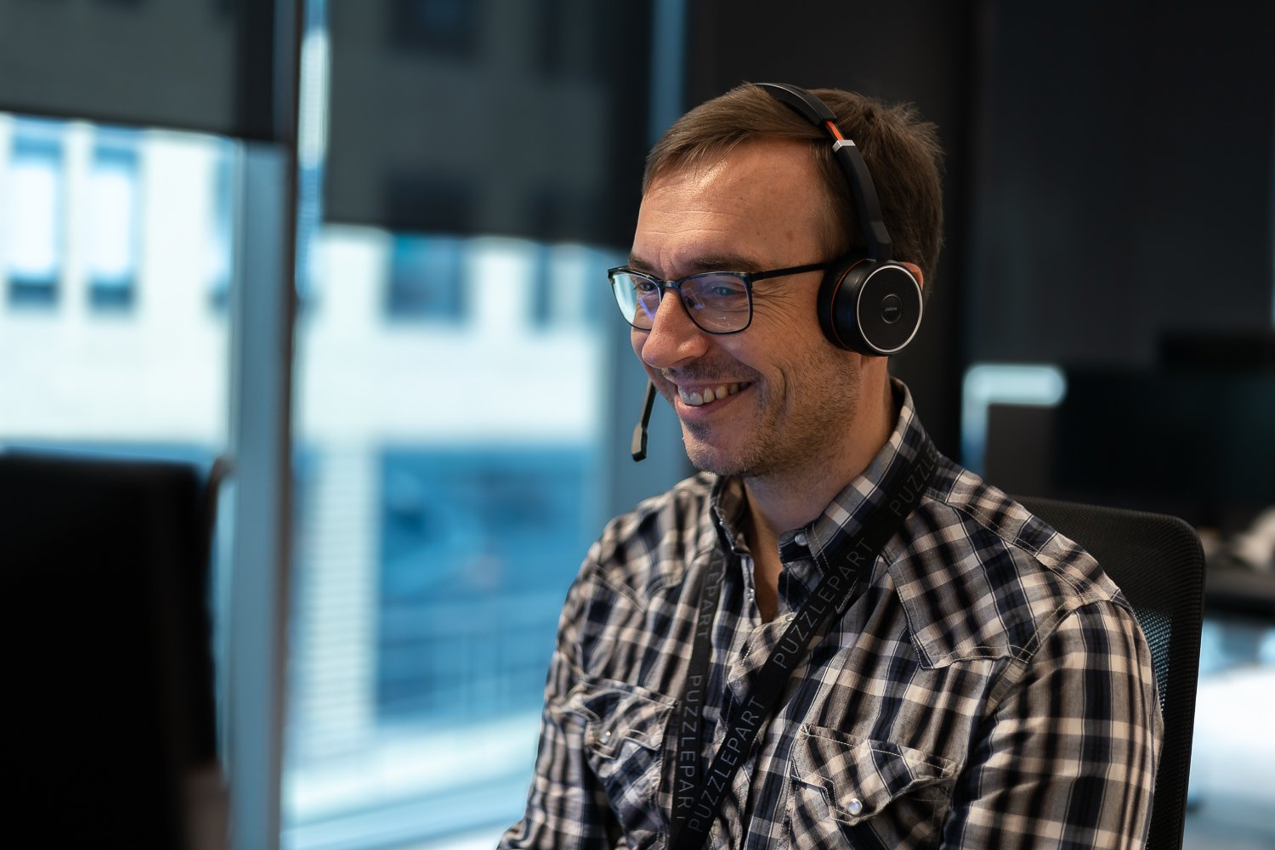 Jan Lindset smiler mens han sitter i et teams-møte på kontoret, med et headset på hodet.