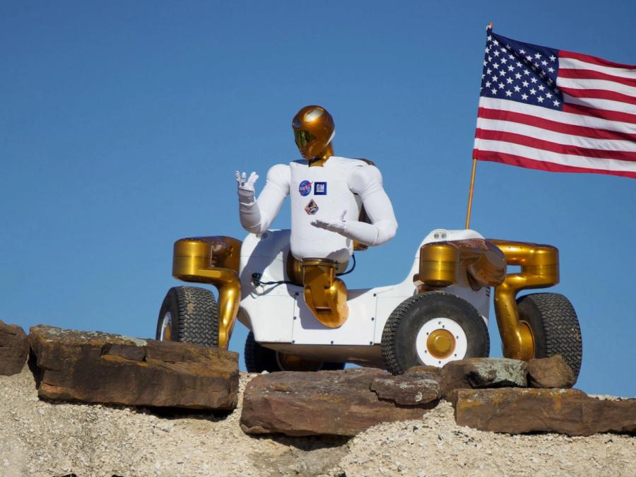 The robotic torso and arms is affixed to the side of a four wheeled rover vehicle.