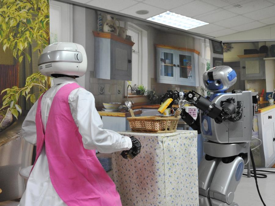 Two robots in a kitchen preparing a basket of food.