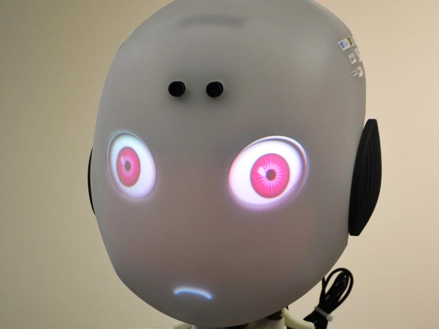 Close-up of the robots glowing pink eyes and downturned mouth.