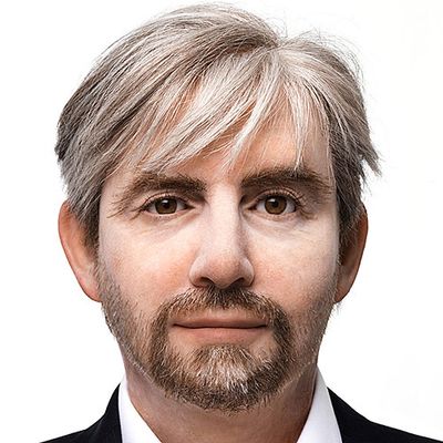 A highly realistic humanoid robot that looks like a brown-eyed man with white blonde hair, a mustache and beard.