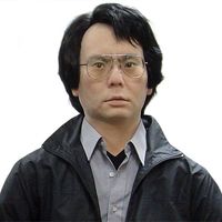 A robot that appears as a Japanese man with glasses, dark hair and eyes, a blue button down shirt and dark jacket.