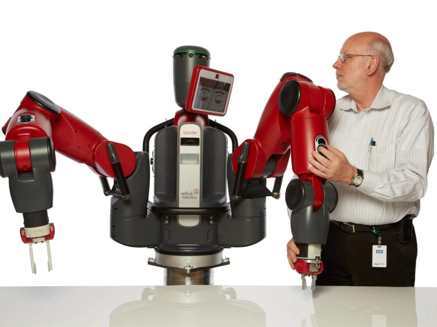 A man holds the arm of an industrial looking robot.