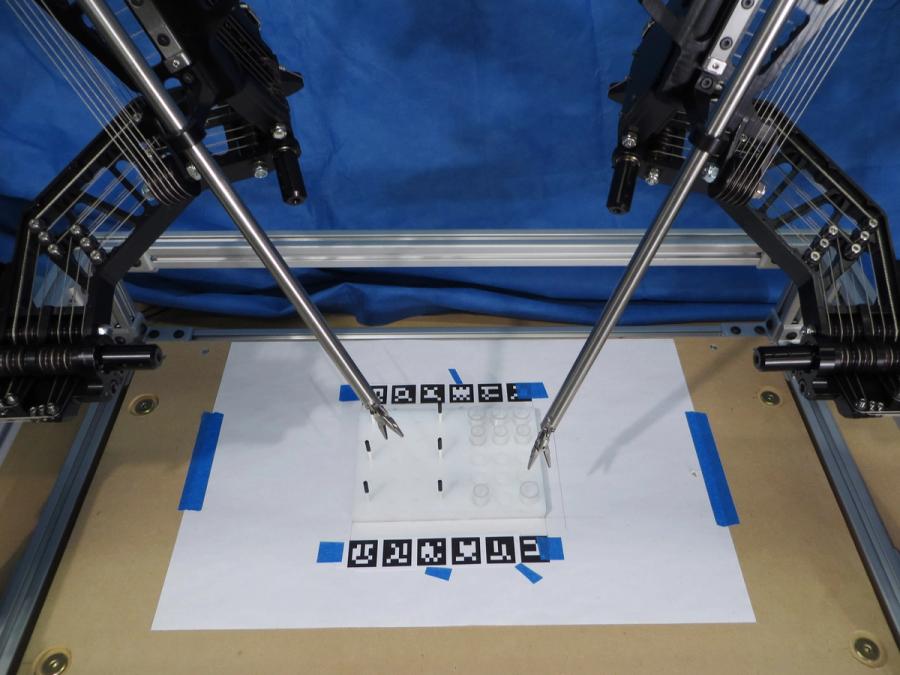Close up of two robotic tools over a white piece of paper with vision recognition patterns.