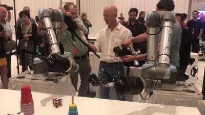 Amazon CEO Jeff Bezos tries the tactile telerobot hands.