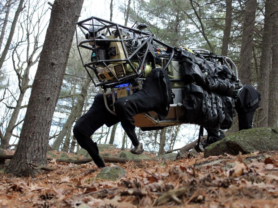 A very large black quadruped robot  in the woods.