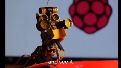 A robot's head with cameras, sensors, and wires looks to the right of the frame, with the logo of the Raspberry Pi in the background.