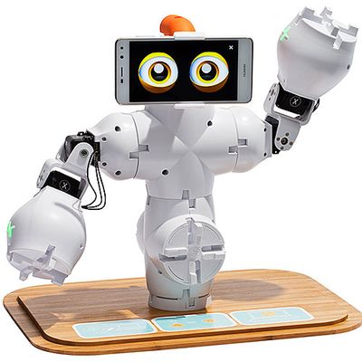 A modular white robot with a small torso, arms and a phone displaying expressive eyes sits on a wooden tabletop base.