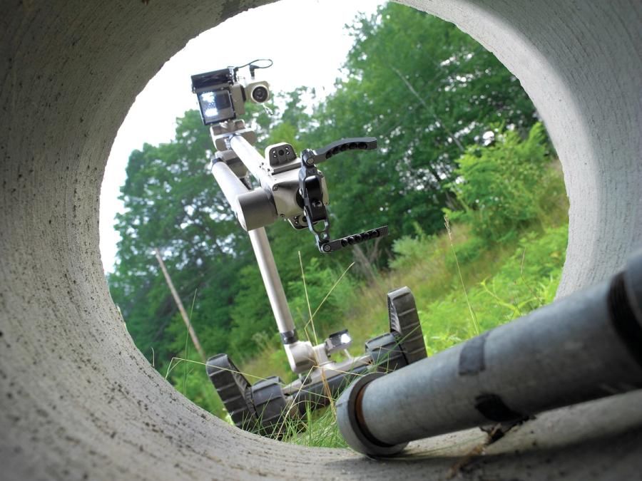 View from inside a concrete tunnel shows the robot reaching towards a cylinder.