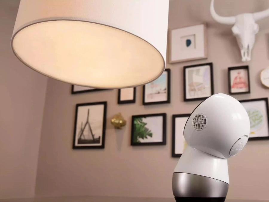 The robot looks up at a large lamp.