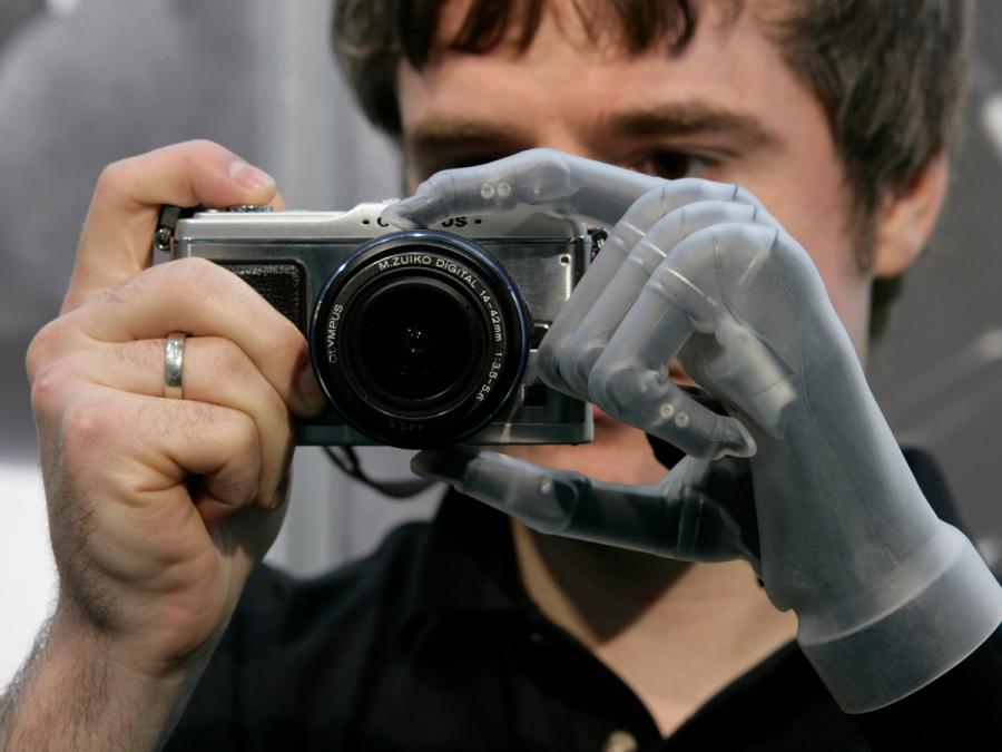 A man with a prosthetic hand holds a camera with both hands.