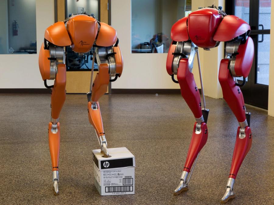 An orange legged robot and a red legged robot.