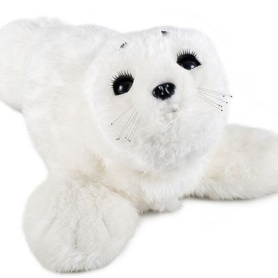 A furry white robot which looks like a baby harp seal looks up at the camera.