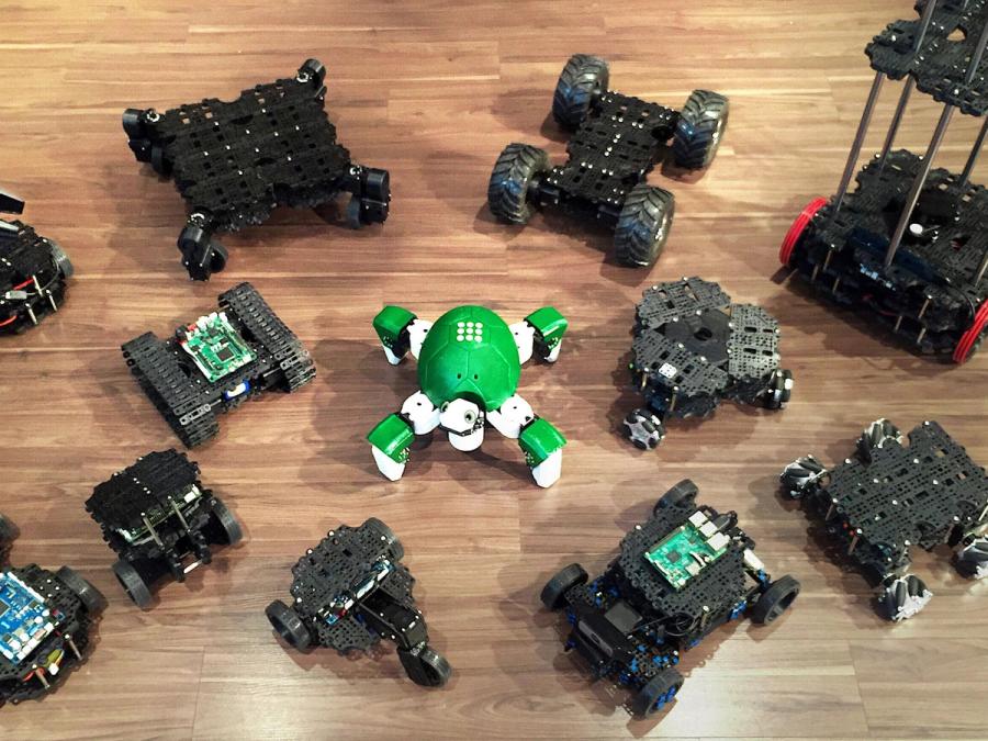 A dozen configurations of TurtleBot 3 in varying shapes and sizes on a wooden floor.